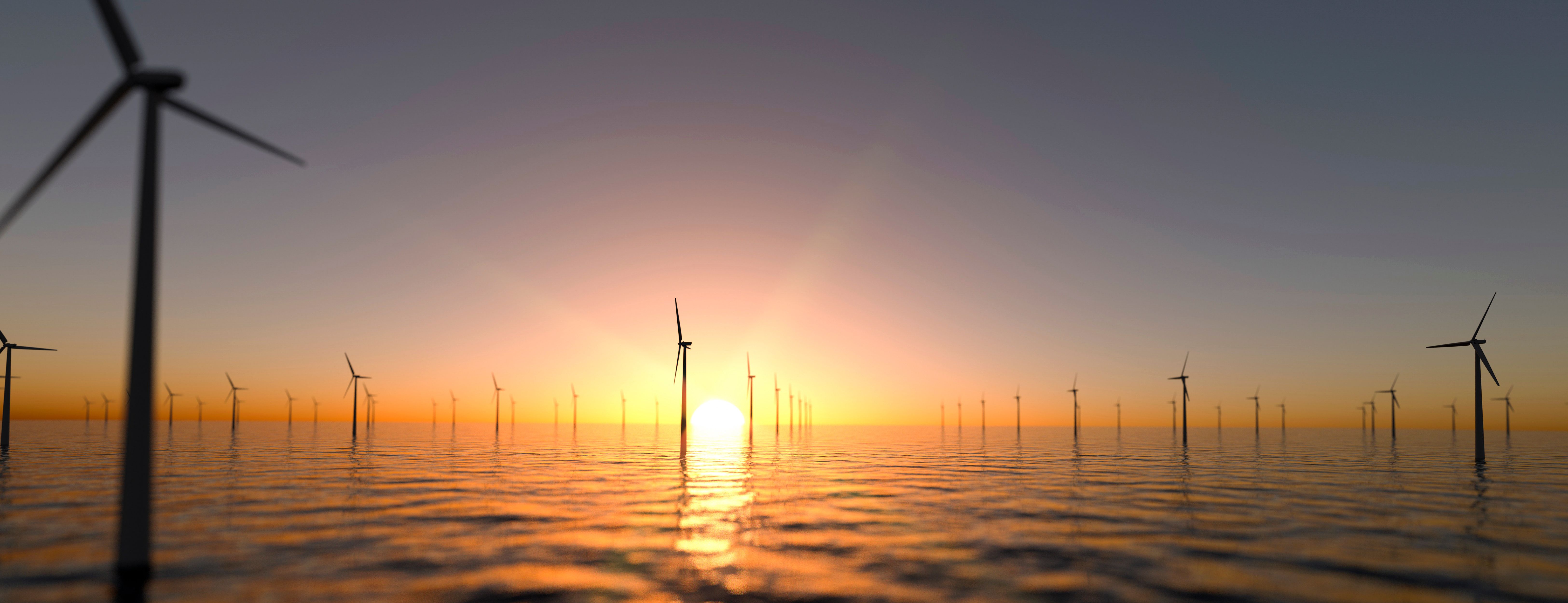 Orange sun setting behind an offshore wind farm