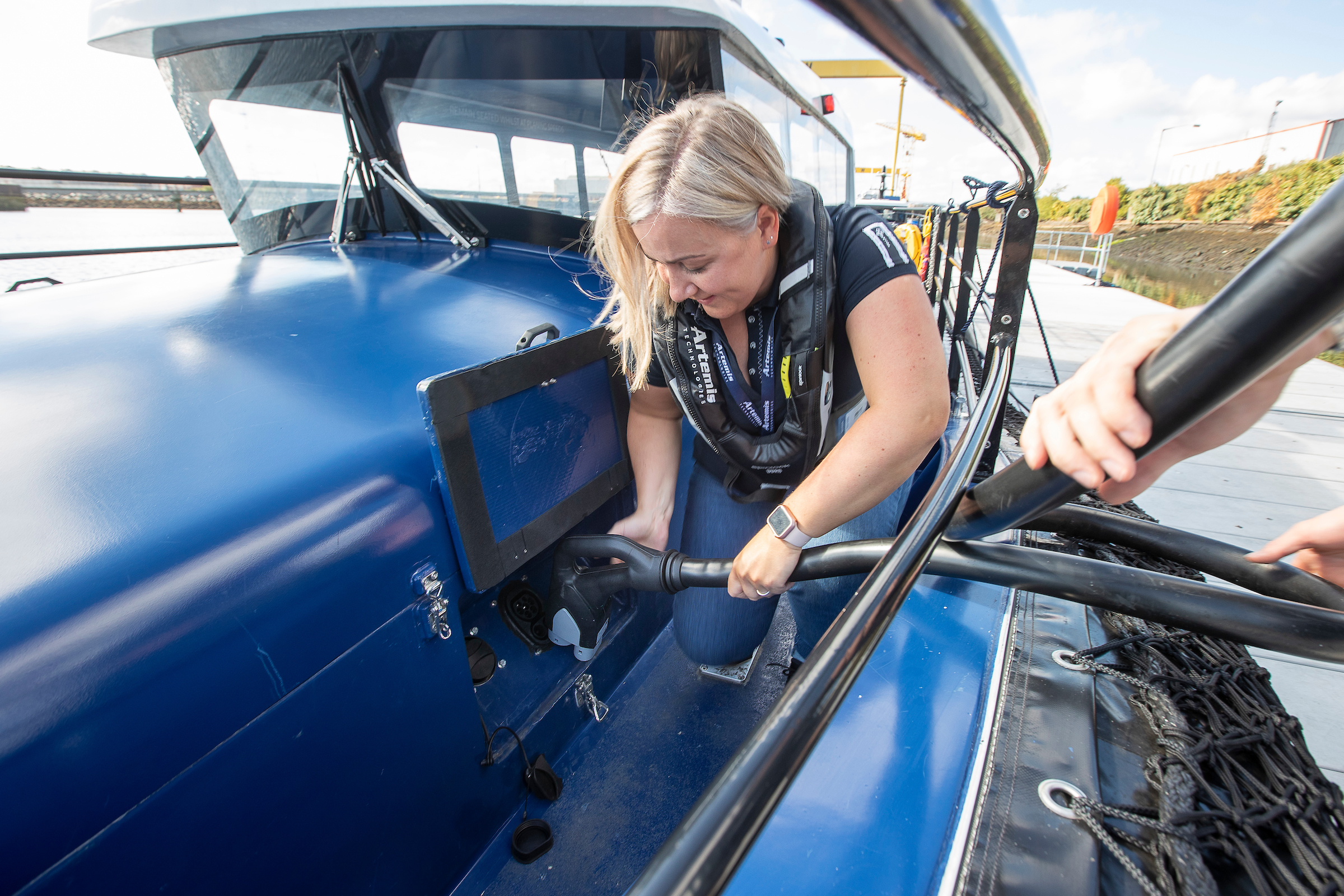 A woman putting a charger into an electric boat