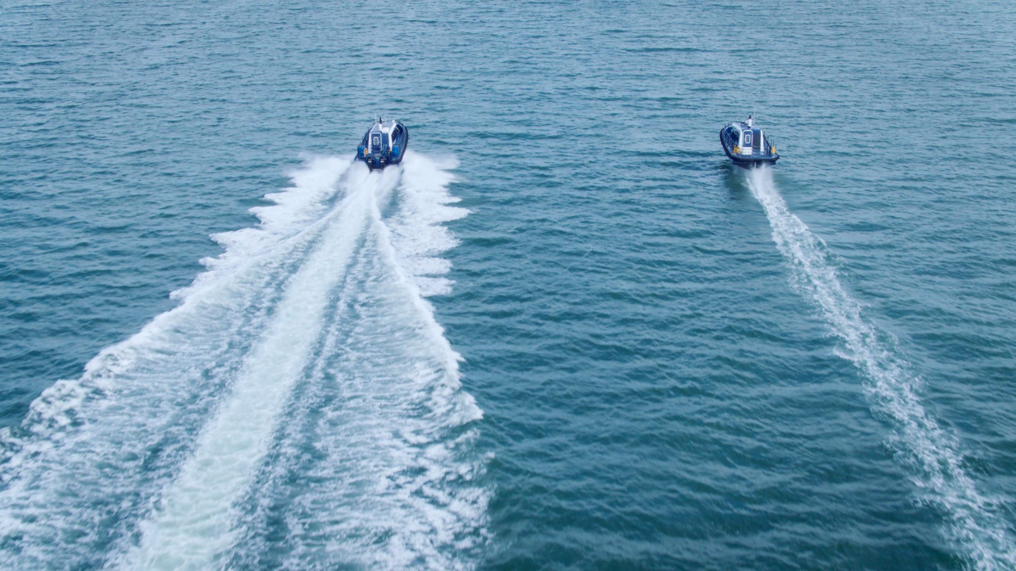Artemis EF-12 Workboat foiling with minimal wake behind it and Seahorse, a displacement vessel sailing parallel but producing a much larger wake behind it