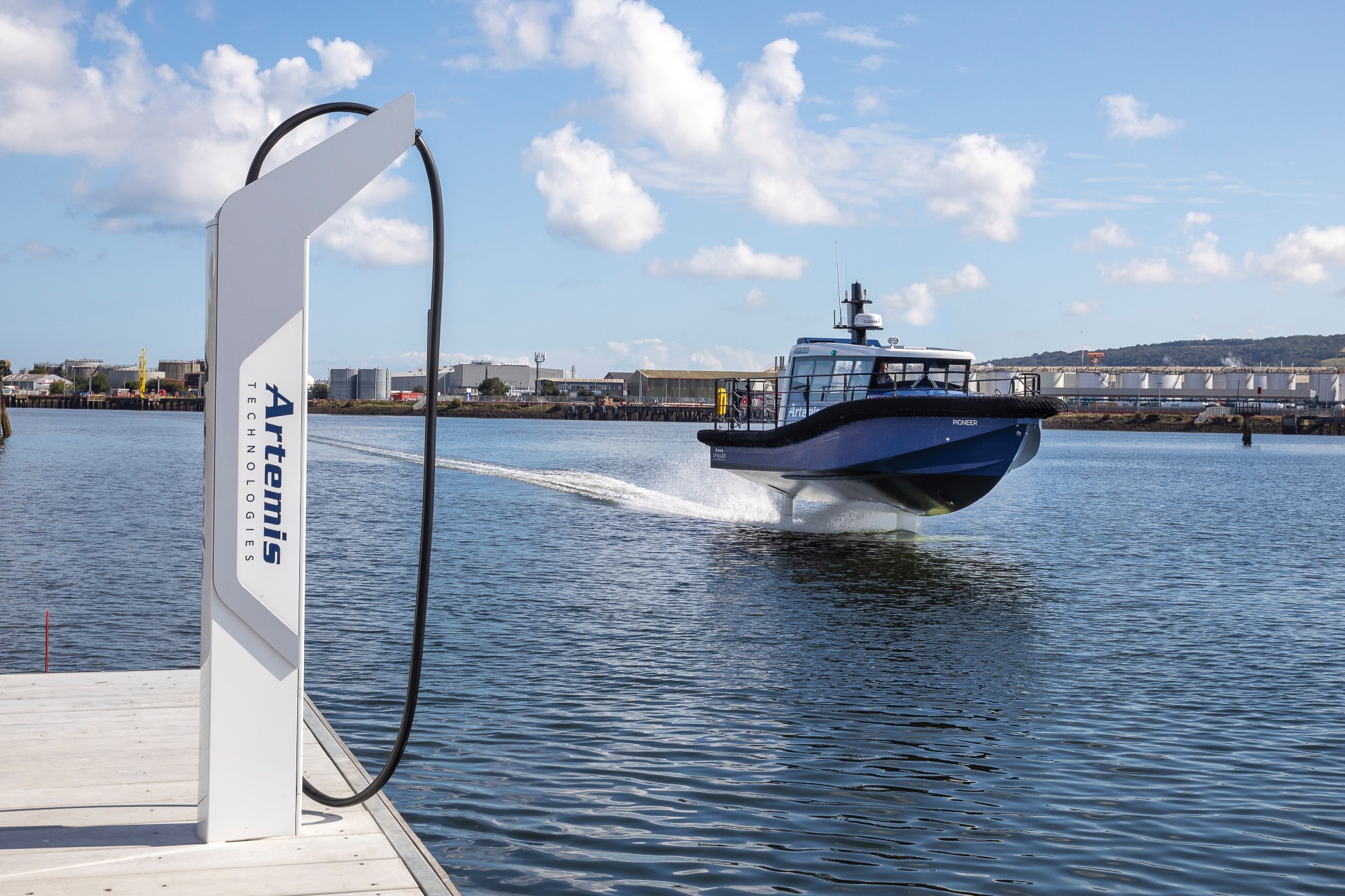 Artemis EF-12 Workboat foiling beside the pontoon with the high speed charger with Artemis Technologies logo on the side