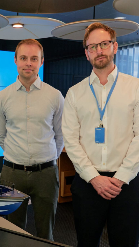 David Tyler standing with one other in conference room, infront of Artemis Technologies EF-12 Water taxi model