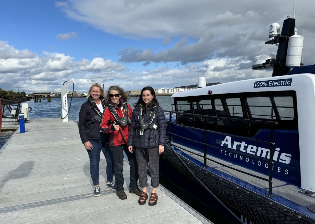 Madadh McClean, Gail Cook and Abi Henry standing on a pontoon in front of the navy EF-12 Workboat