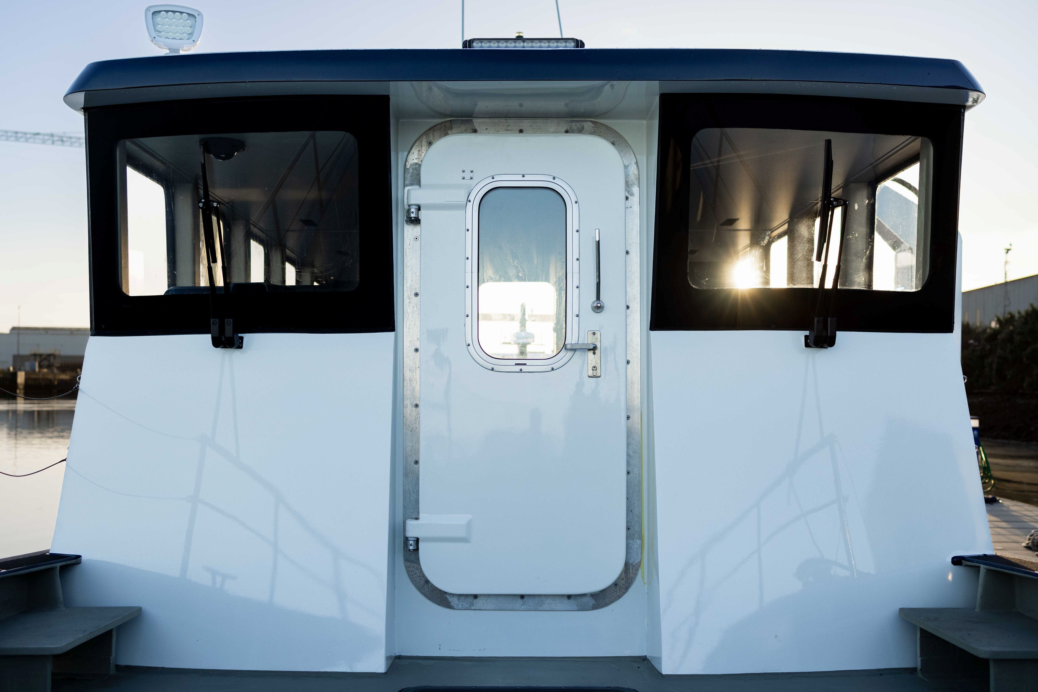An image of the front of the white Artemis EF-12 Workboat's wheelhouse. With a door in the middle and windows on either side with wipers on them