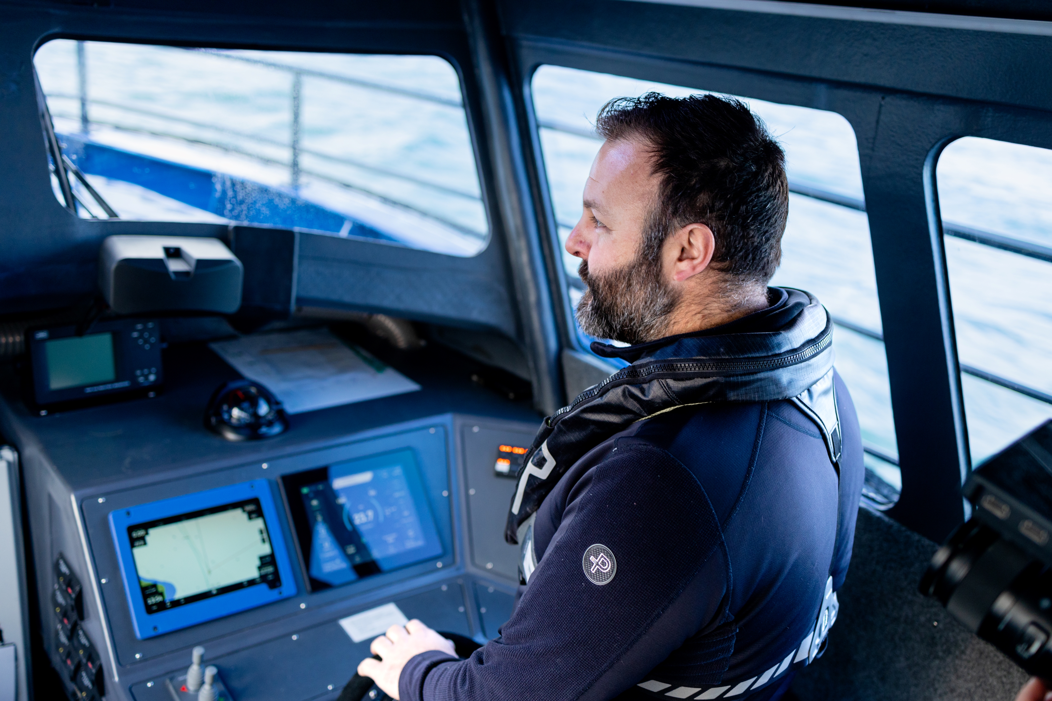 Man piloting a boat sitting at the wheel with a screen display in front of him