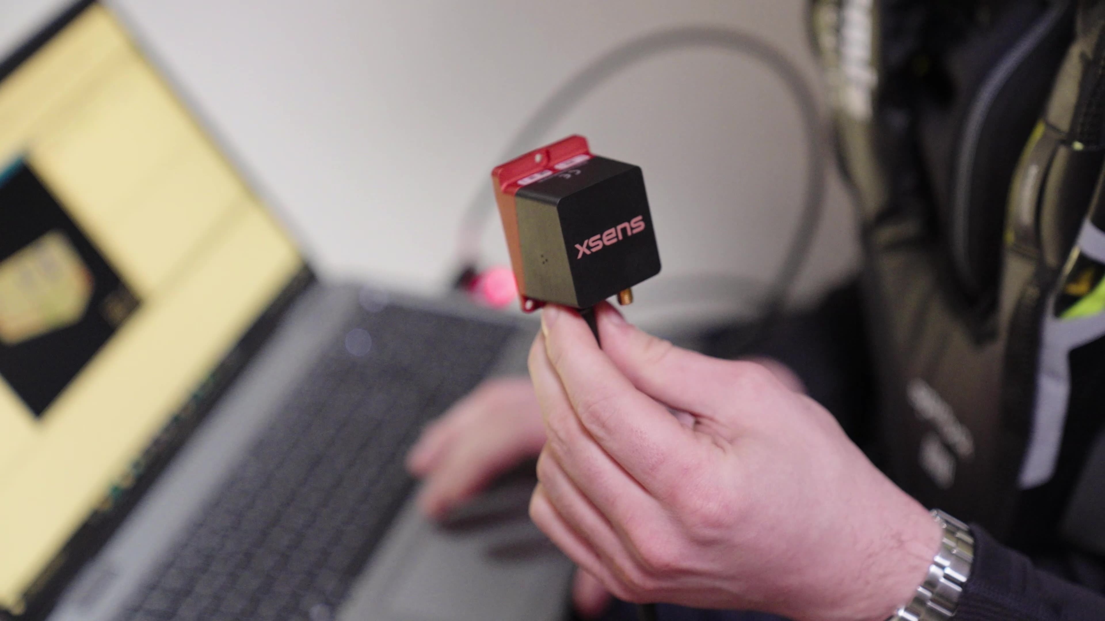 a close up of someone holding the inertial measurement unit with a computer in the background.