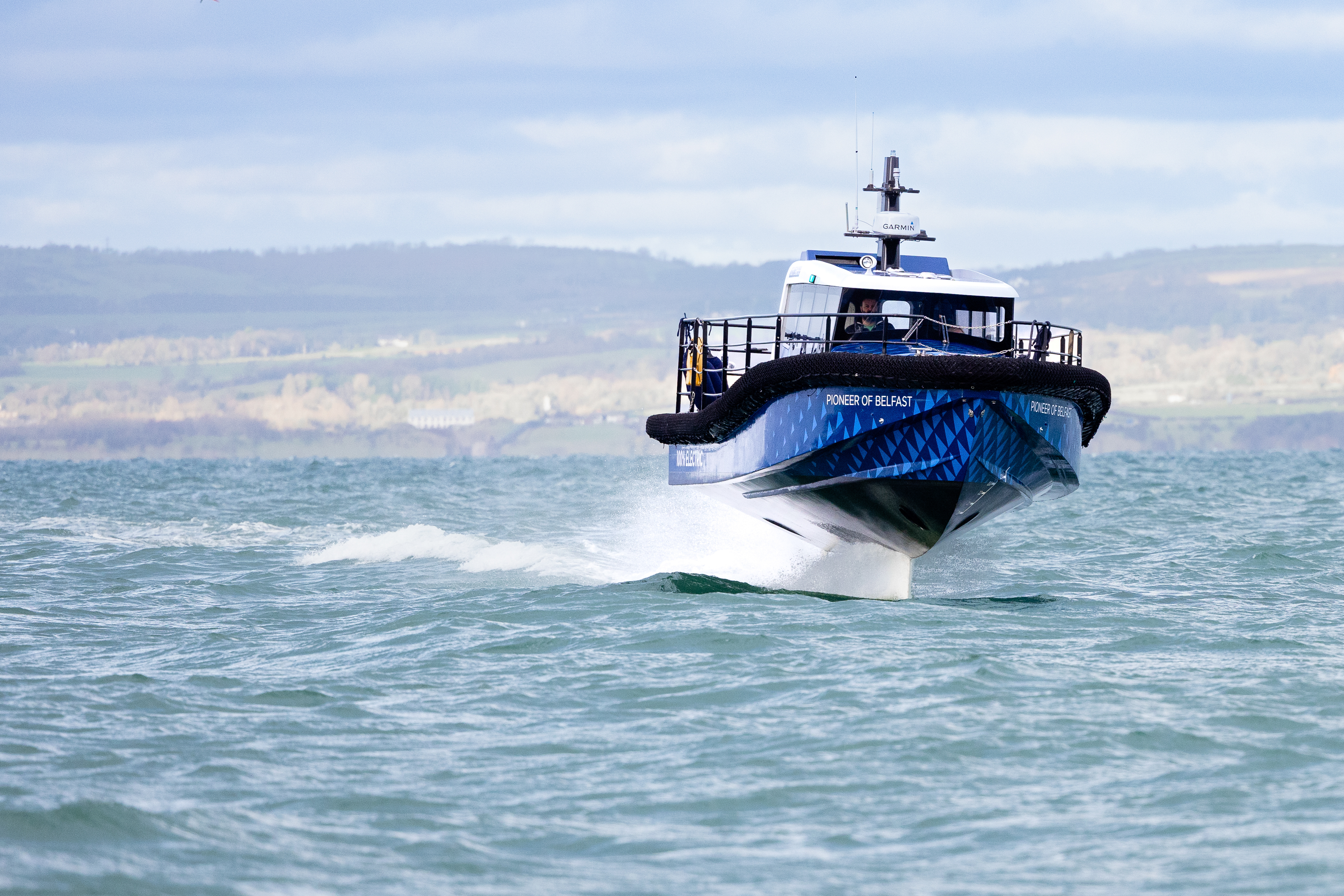 Blue EF-12 Workboat foiling towards the camera with a hill in the background