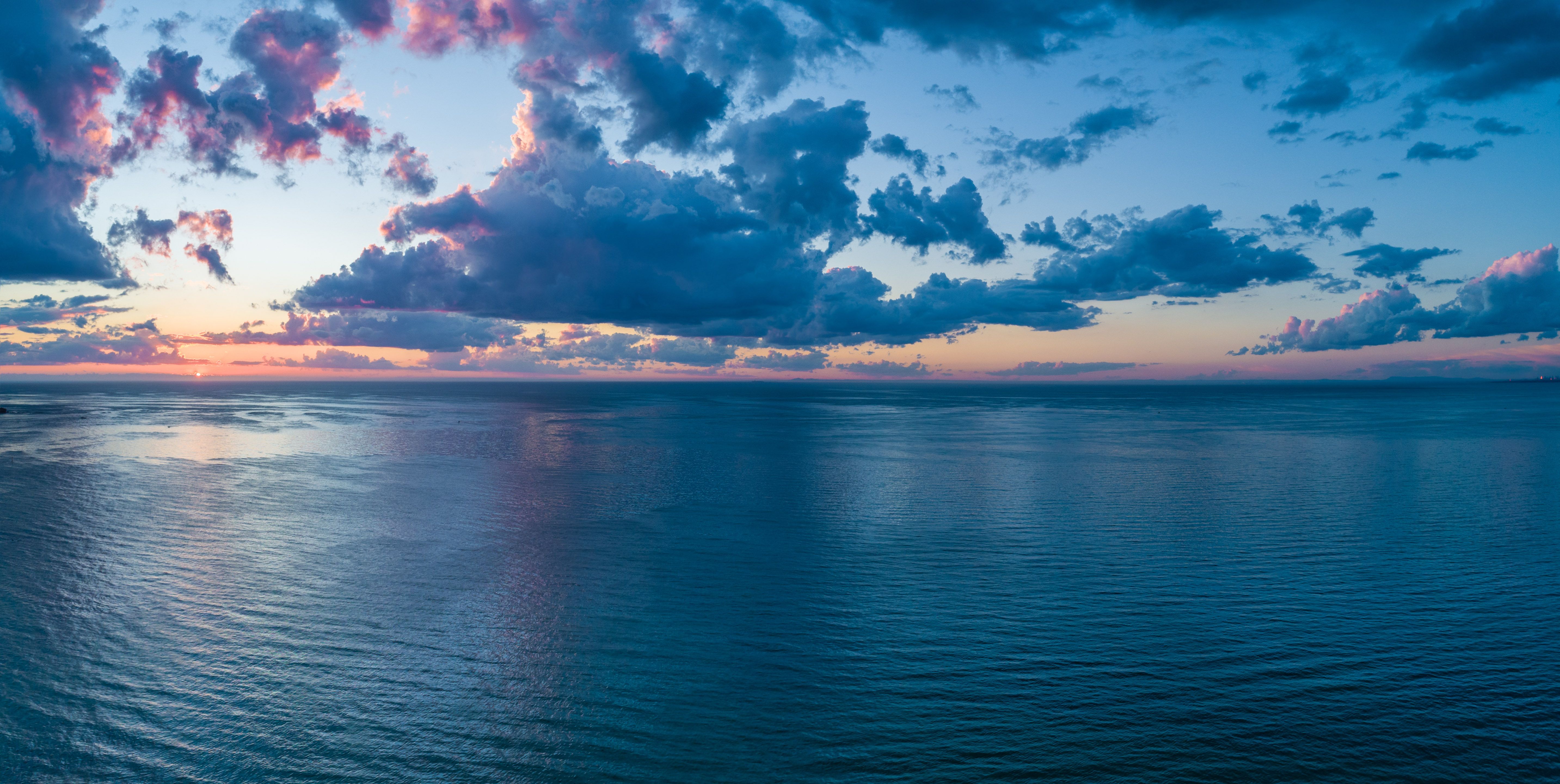 The sun rising over the sea with clouds in the sky