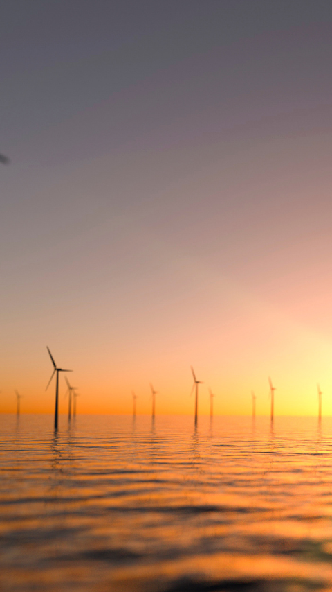 Orange sun setting behind an offshore wind farm